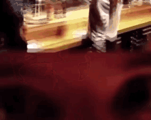a blurred image of a person standing in front of a table with glasses on it