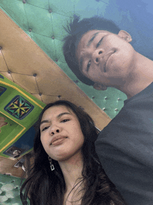a man and a woman are posing for a picture with a green cushioned ceiling in the background