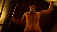 a man in an orange shirt and black hat is standing in the dark