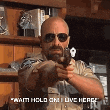 a man holding a gun with the words " wait hold on i live here " on the bottom