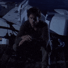 a man in a black shirt is kneeling on a boat in the dark
