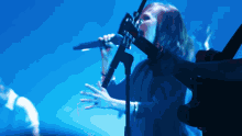 a woman is singing into a microphone while playing a guitar