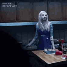 a woman in a blue dress is standing in a kitchen with a reface app logo