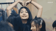 a group of girls are making a heart shape with their hands and the word fever is on the bottom right