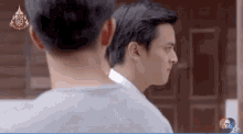 two men are standing next to each other in front of a door with the number 7 on it .