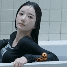 a woman in a bathtub with a sea otter laying on the edge