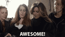 a group of people are looking at a cell phone and one of them is saying awesome