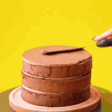 a person is cutting a cake with a knife on a yellow background