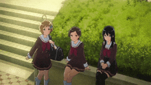 three girls in school uniforms sit on a sidewalk