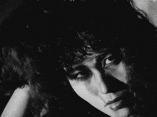 a black and white photo of a woman with curly hair looking at the camera