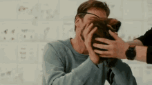 a man is petting a cat on his face while wearing glasses .