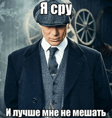 a man in a suit and tie is standing in front of wagon wheels