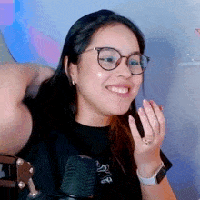 a woman wearing glasses and a watch is sitting in front of a microphone .