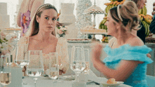 two women are sitting at a table with glasses of wine