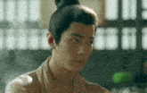 a man with a bun on his head is sitting in a room .