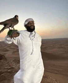 a man is holding a bird on his shoulder in the desert