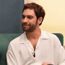a man with a beard is sitting on a green couch