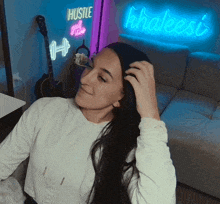 a woman is sitting in front of a neon sign that says khaleesi