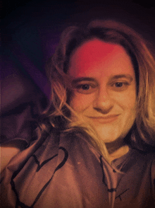 a woman wearing a shirt with a heart on it is smiling