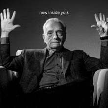 a man sitting in a chair with his hands up and the words new inside yolk below him