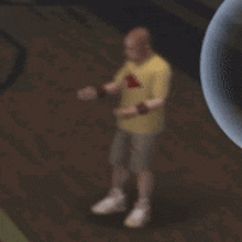 a man in a yellow shirt and shorts is standing in front of a bubble .