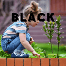 a little girl squatting on a brick wall with the word black above her head