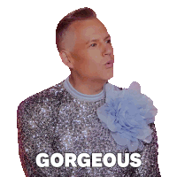 a man wearing a sequined sweater with a blue flower on his collar says gorgeous