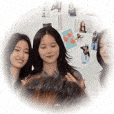 a group of young women are standing next to each other in front of a wall covered in pictures .