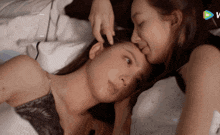 two women are laying on a bed and one is touching the other 's hair