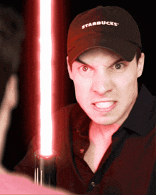 a man wearing a starbucks hat holds a light saber