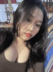 a woman wearing a necklace with a cat on it looks at the camera