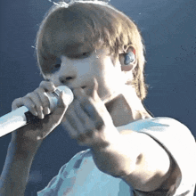 a young man singing into a microphone with ear buds on