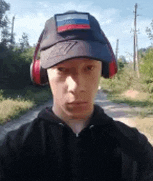 a young man wearing a hat and headphones is taking a picture of himself .