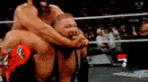a wrestler is carrying another wrestler on his shoulders during a wrestling match .
