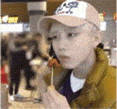 a man wearing a hat is eating something on a stick ..