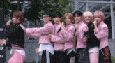 a group of young men in pink jackets are posing for a picture with a sign that says i want milkz