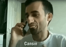 a man is smiling while talking on a cell phone and the word cansin is on the screen .