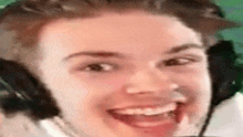 a man wearing headphones is smiling with his mouth open .