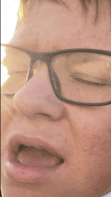 a close up of a person wearing glasses with their eyes closed