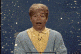 a man wearing a blue sweater and a yellow shirt is making a face