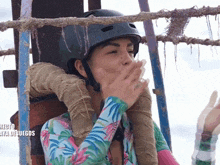 a woman wearing a helmet is covering her mouth with her hand and the word juegos is on the bottom