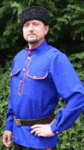 a man wearing a blue shirt and a black hat is standing with his hands on his hips