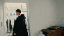 a man in a black coat stands in a room