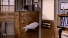 a model airship is sitting on a filing cabinet in a room next to a bookshelf .