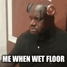 a man wearing headphones is sitting in front of a door and says `` me when wet floor '' .