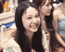 a girl with long hair is smiling with a blue bottle of water in the background