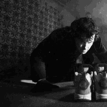 a black and white photo of a man laying on the floor with a pair of nike shoes on his feet