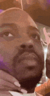 a close up of a man 's face with a woman 's hand on his neck .