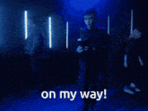 a man in a blue coat is holding a trophy and the words on my way are above him