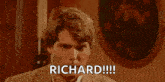 a man is sitting in a chair and pointing at the camera with the words `` richard !!! '' written on his face .
